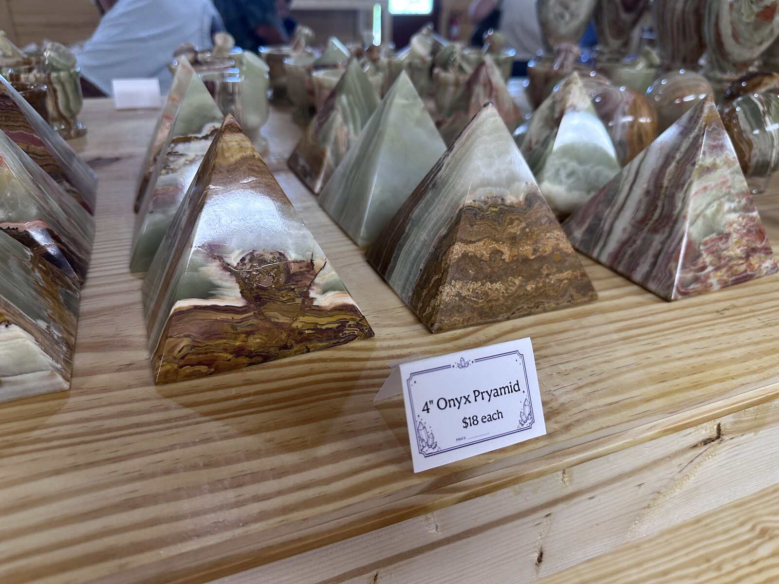 Rows of four-inch banded onyx pyramids in green and brown on a pine table